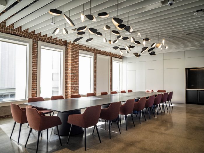 A meeting room at the Autodesk Gallery with a long table and sculptural pendant lighting